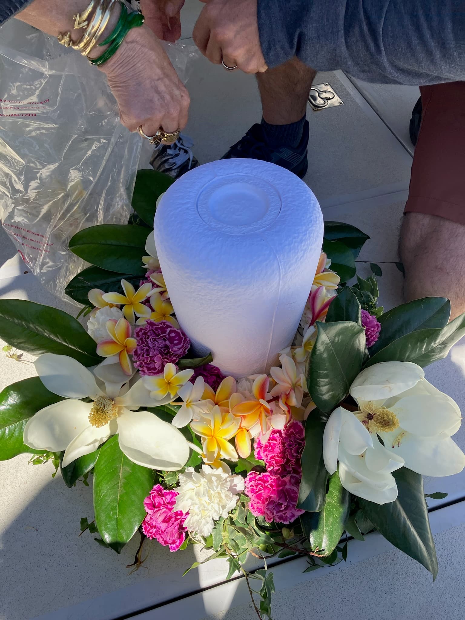 A white water-soluble urn wreathed in plumeria and magnolia, prepared on deck.